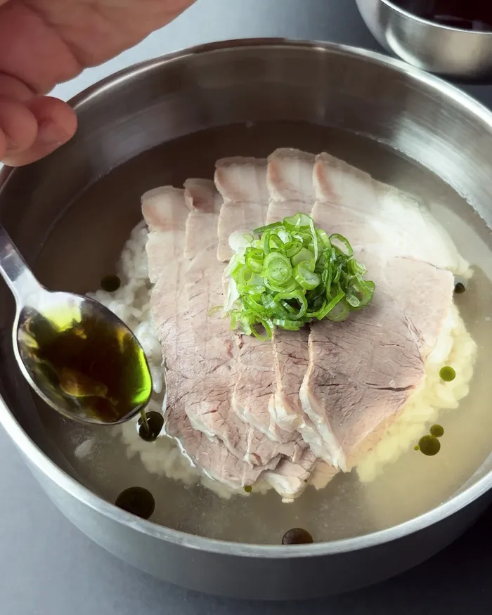 A bowl of gomtang topped with sliced pork and green onion
