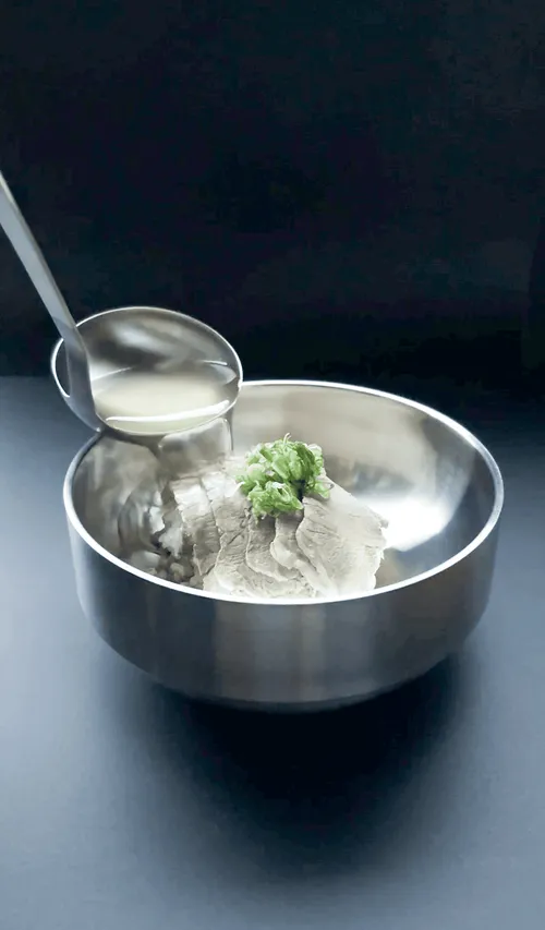 Broth being ladled over a bowl of gomtang