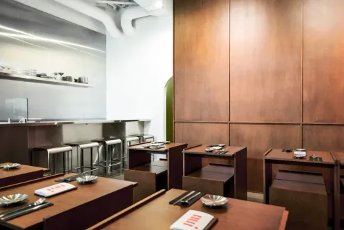 The Nui dining room, with wooden tables and a steel counter with stools