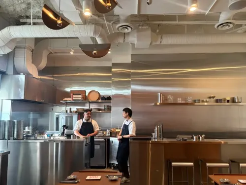Two Nui chefs talking in the open kitchen behind the steel counter