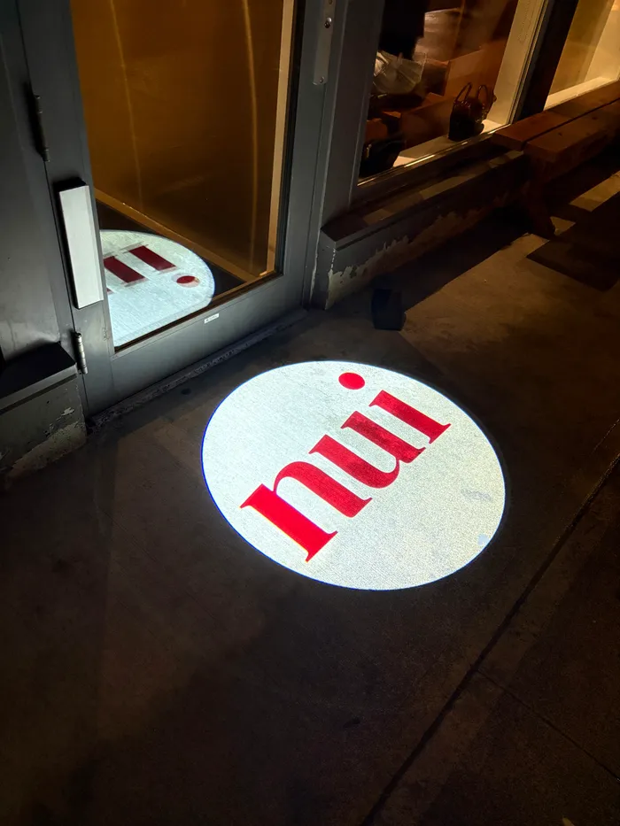 The Nui logo projected on the pavement outside the front door