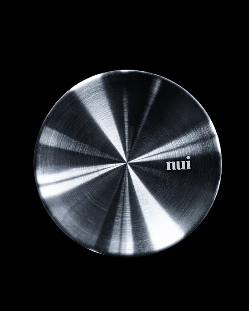 A brushed metal bowl lid engraved with the Nui logo
