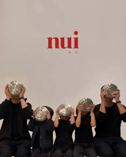 Five people holding steel bowls over their faces beneath the Nui logo