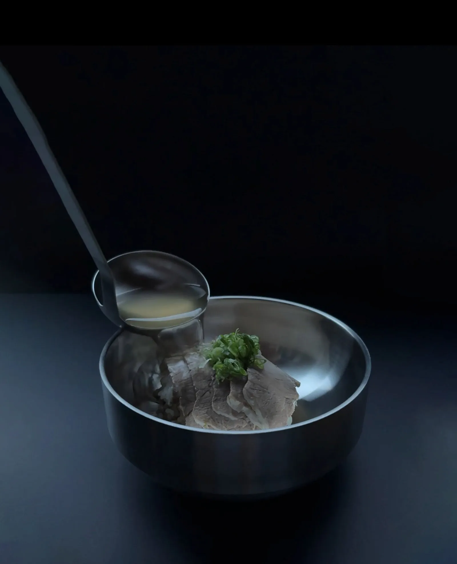 Broth being ladled over a bowl of gomtang